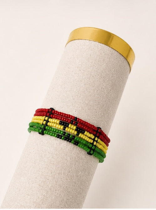 Tintabeads Ghana armband met kralen in rood, geel en groen met een zwart sterpatroon op een beige displayhouder.