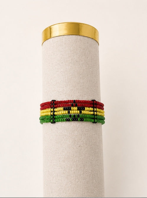 Tintabeads Ghana armband met kralen in rood, geel en groen met een zwart sterontwerp op een displaystandaard.