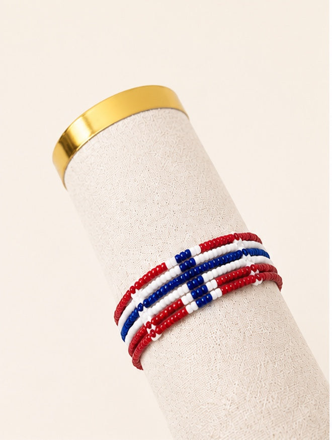 Tintabeads handgemaakte kralenarmband met Noorse vlagpatroon in rood, wit en blauw op een displaystandaard