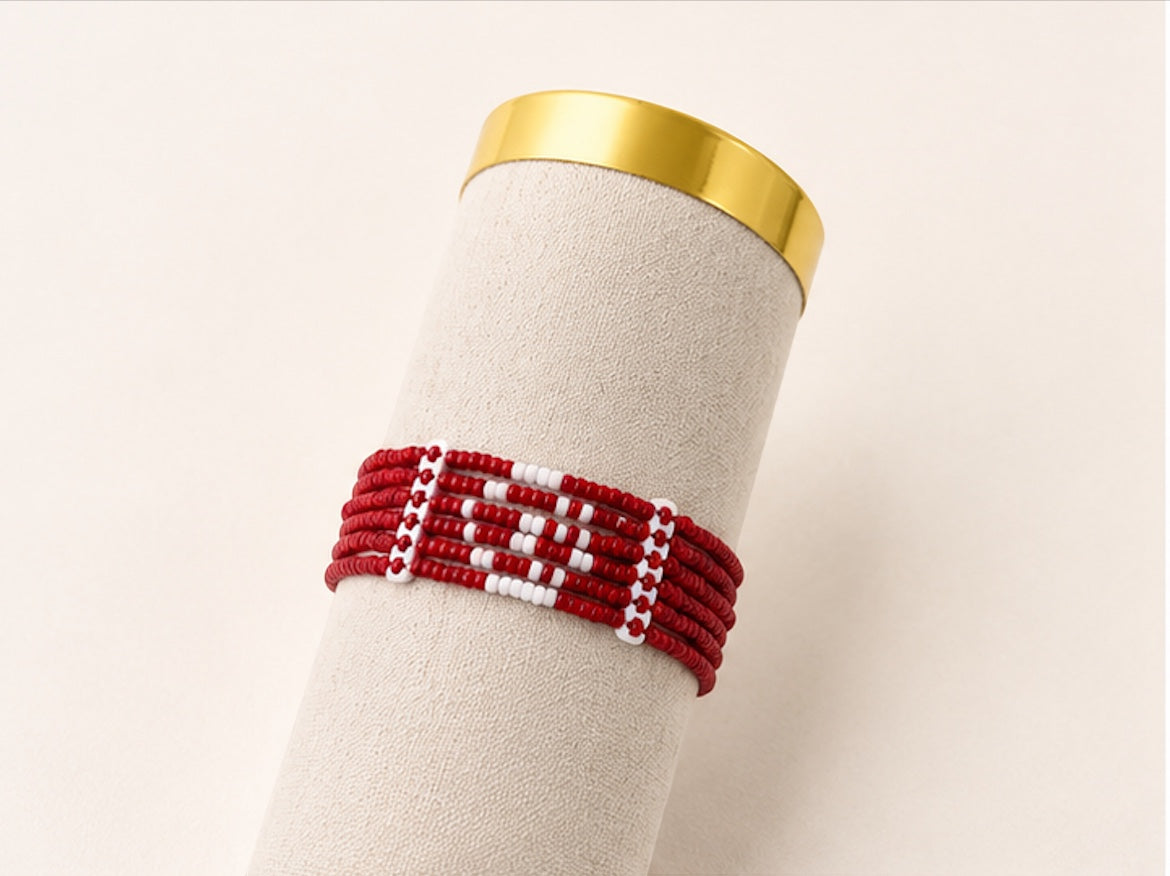 Tintabeads handgemaakte kralenarmband in rood en wit met Tunesisch vlagontwerp op een beige displayhouder.