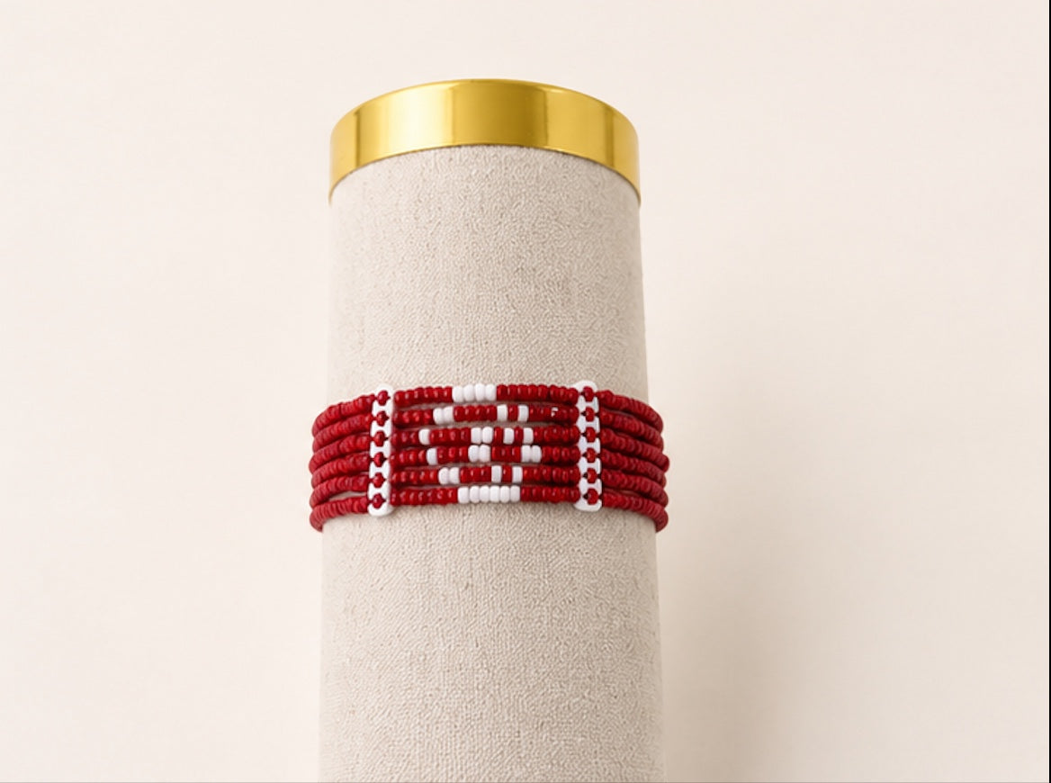 Tintabeads Tunisia armband met rode en witte kralen in een patroon van een halve maan en ster op een beige display.